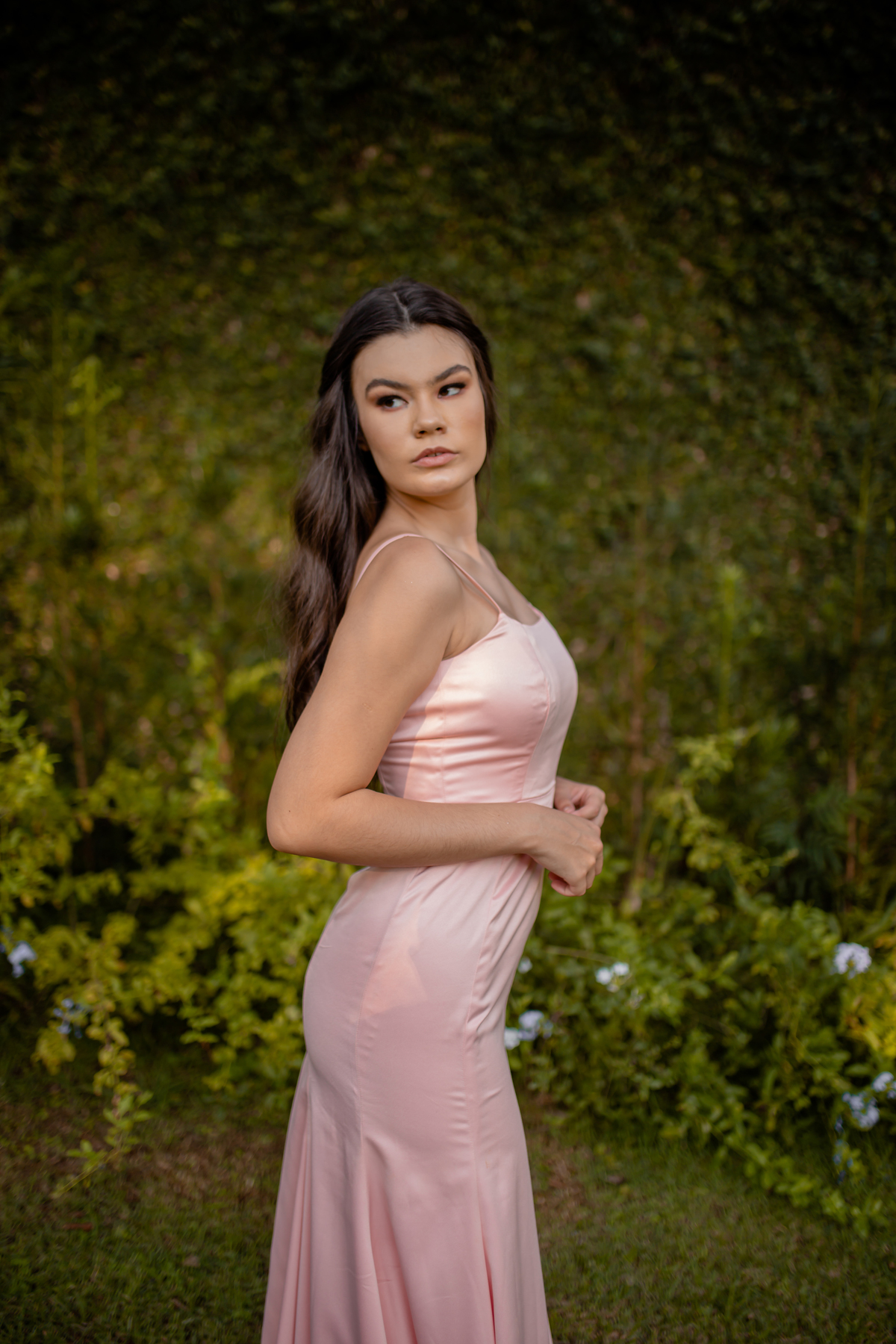 mulher de vestido rose com arvores atrás