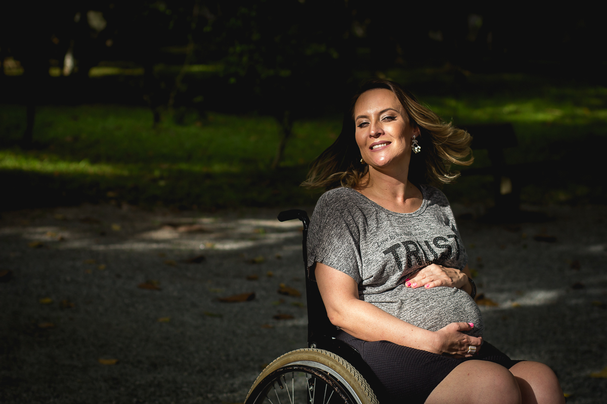 gestante cadeirante sorrindo e com seu cabelo em movimento