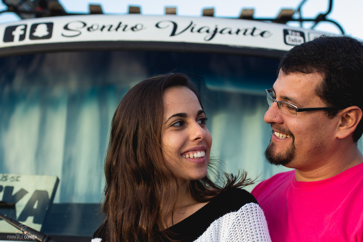casal sorrindo e se olhando em frente de uma kombi