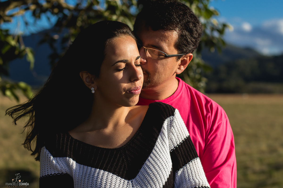casal de olhos fechados abraçados sob a luz do sol