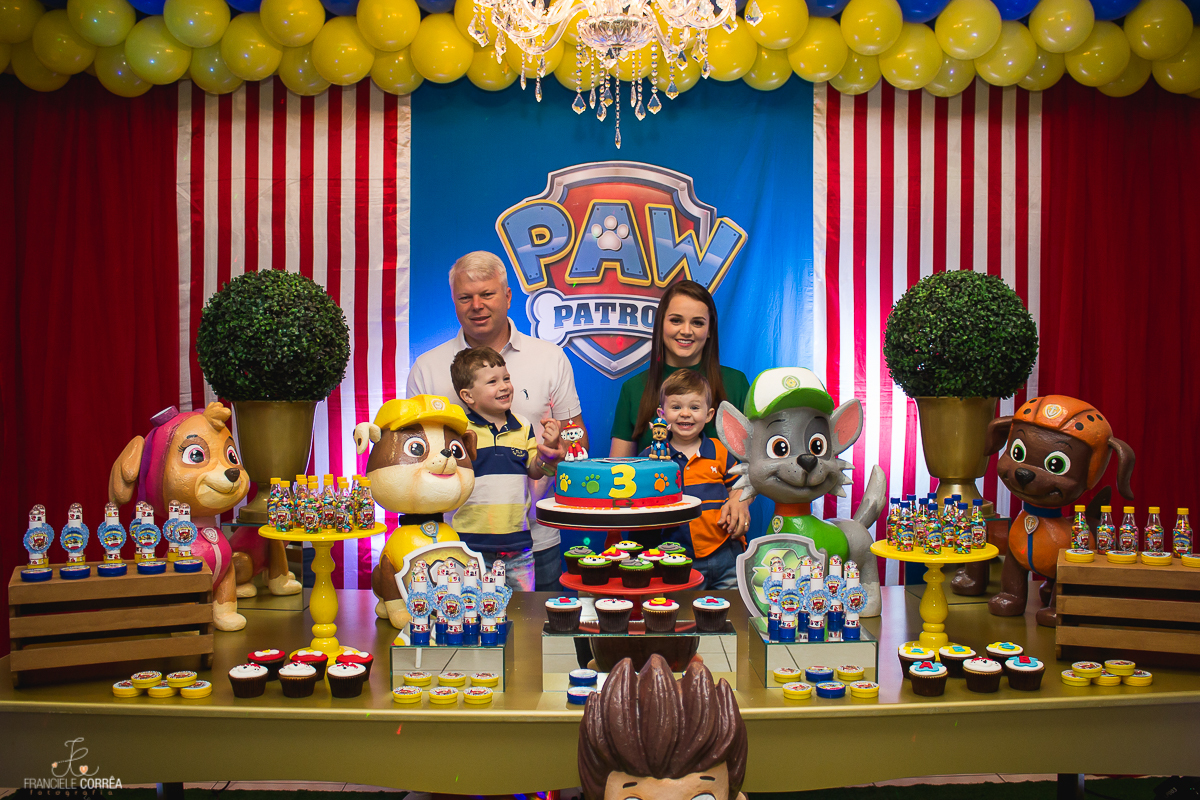 foto dos pais com os aniversariante atrás da mesa do bolo
