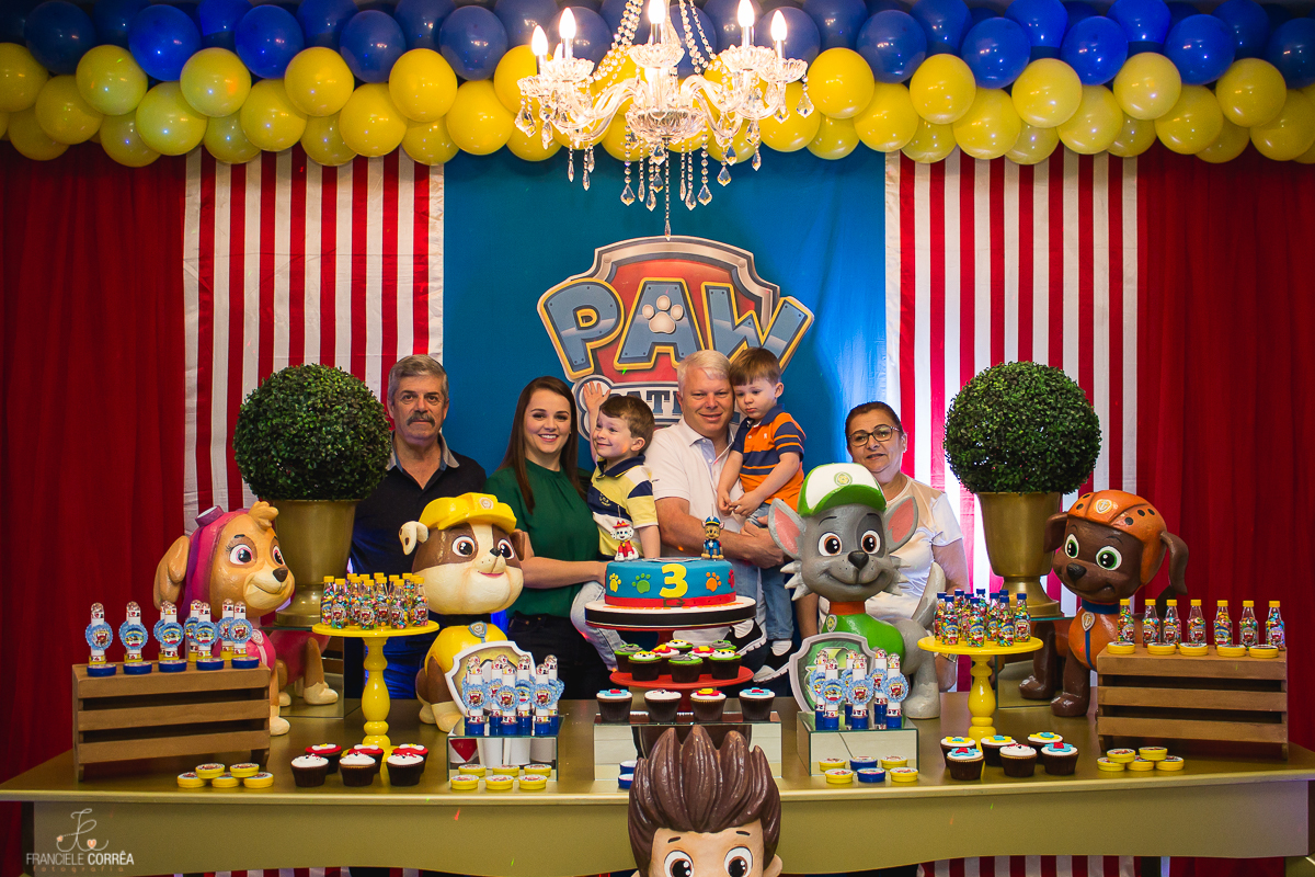 foto dos pais com os aniversariantes e os avós atrás da mesa do bolo