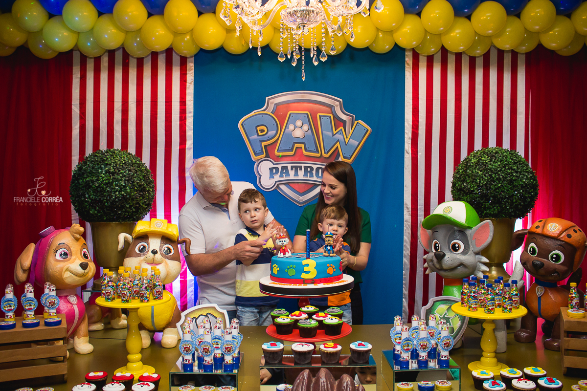 foto dos pais com os aniversariantes atrás do bolo na hora do parabéns