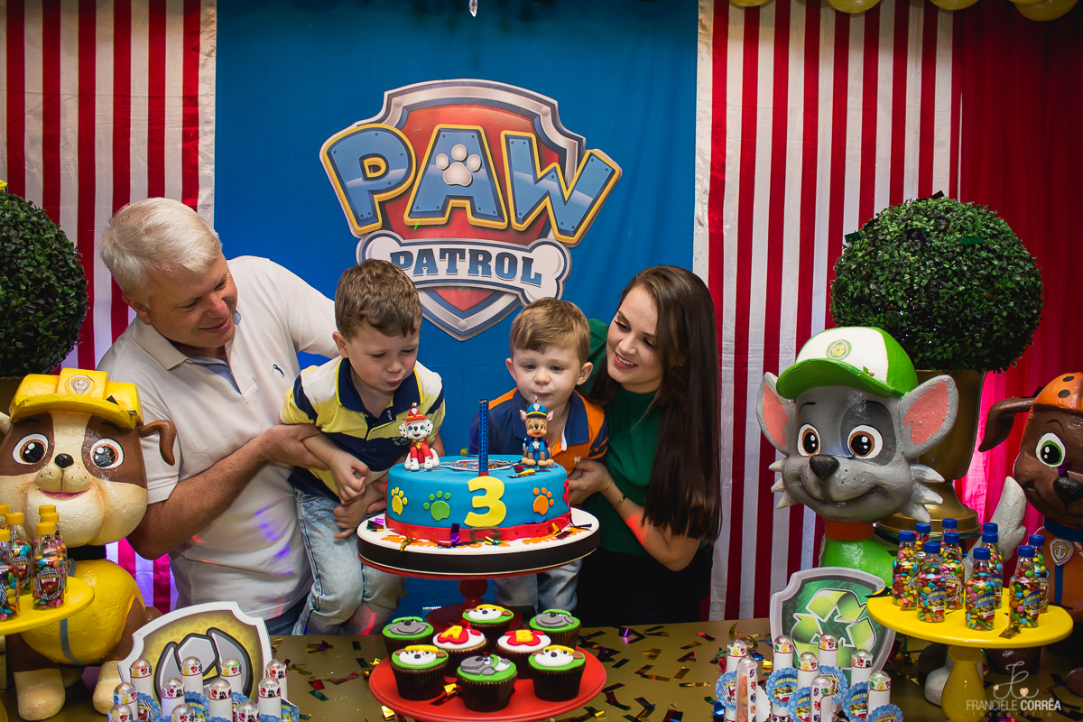 foto dos pais com os aniversariantes assoprando as velinhas