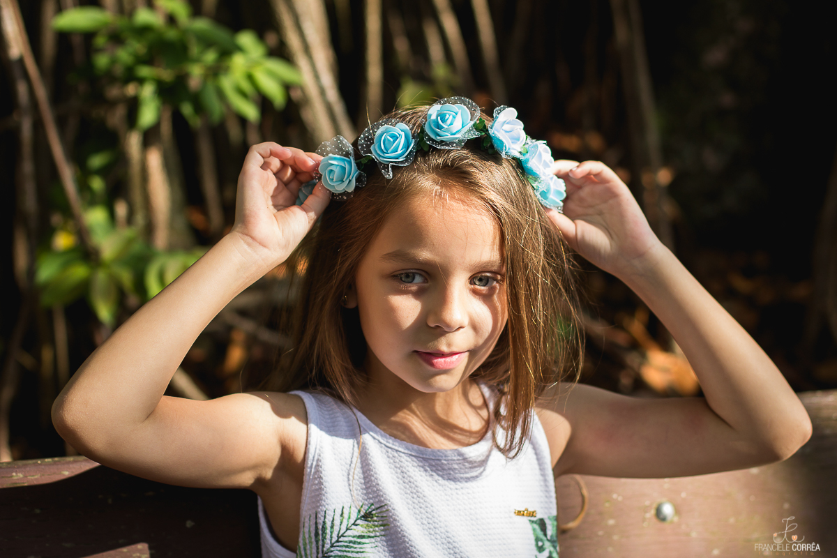 foto menina de olhos azuis colocando uma coroa de flores azuis