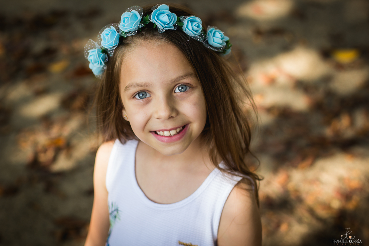 foto menina de olhos azuis com uma coroa de flores azuis sorridente