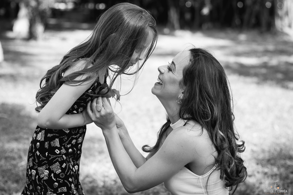 foto em preto e branco da filha entregando uma flor para a mãe