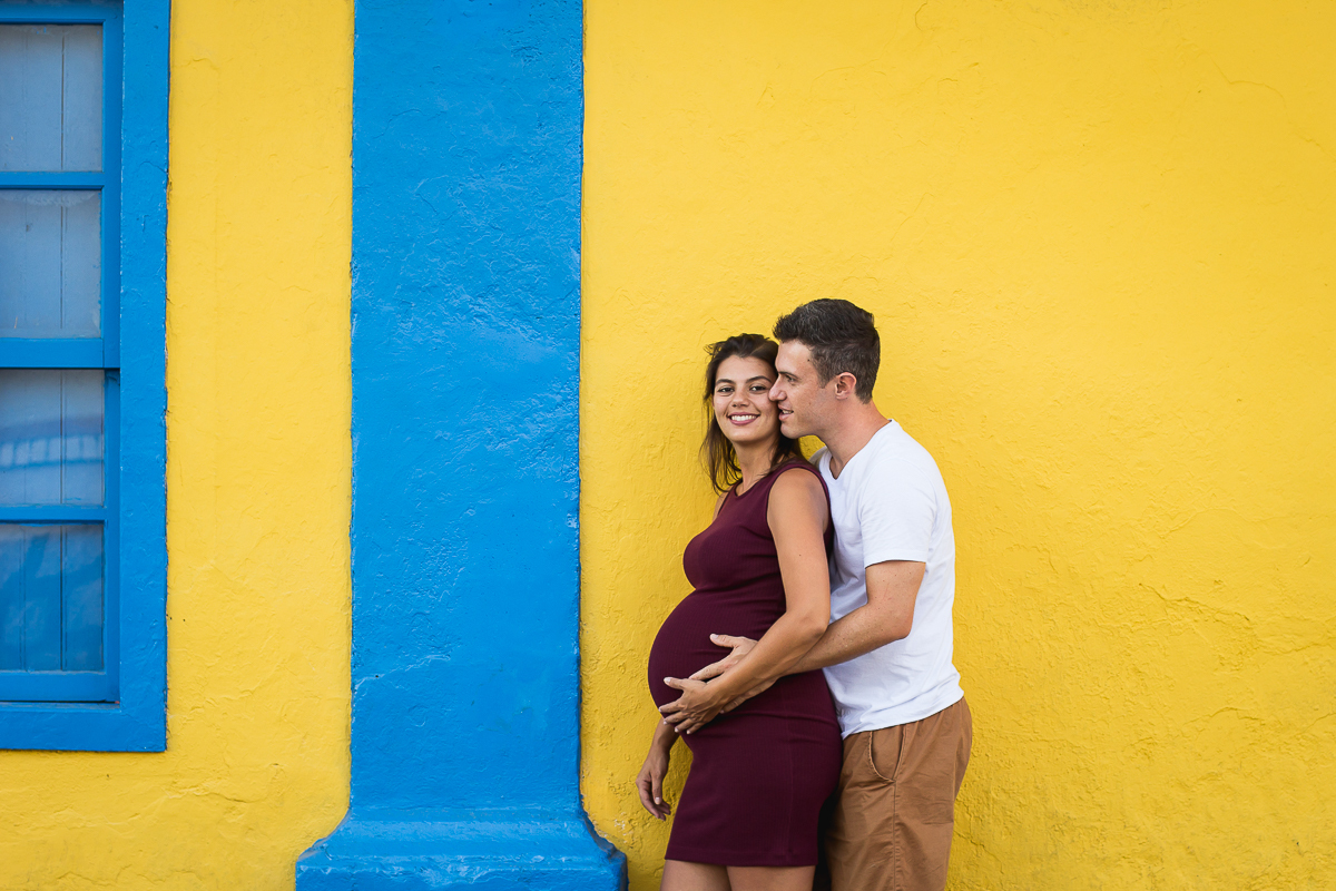 casal abraçados em frente a uma parede amarela