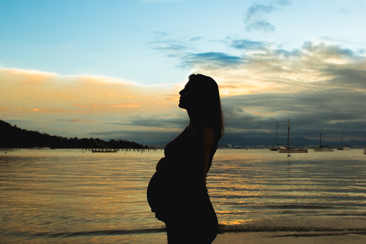 silhueta da gestante na beira da praia em um por do sol em santo antônio de lisboa  florianópolis.
