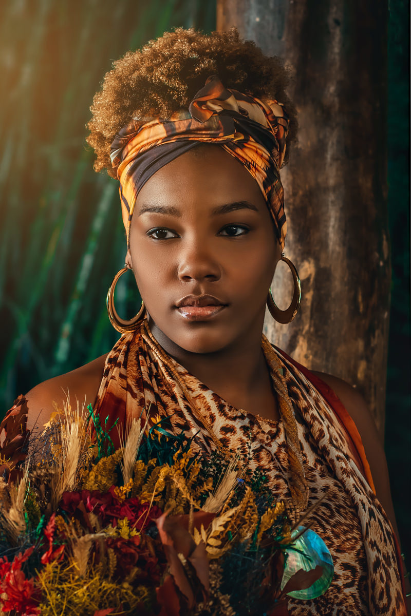 Mulher negra com argolas douradas, roupa com estampa de onça, e segunda um ramo de flores