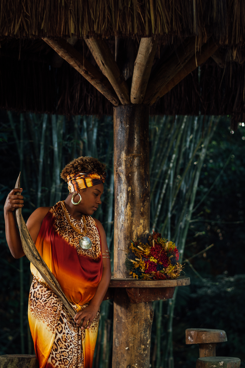 Gestante negra com vestido de estampa africana, segurando um ornamento feita com a palha de coqueiro