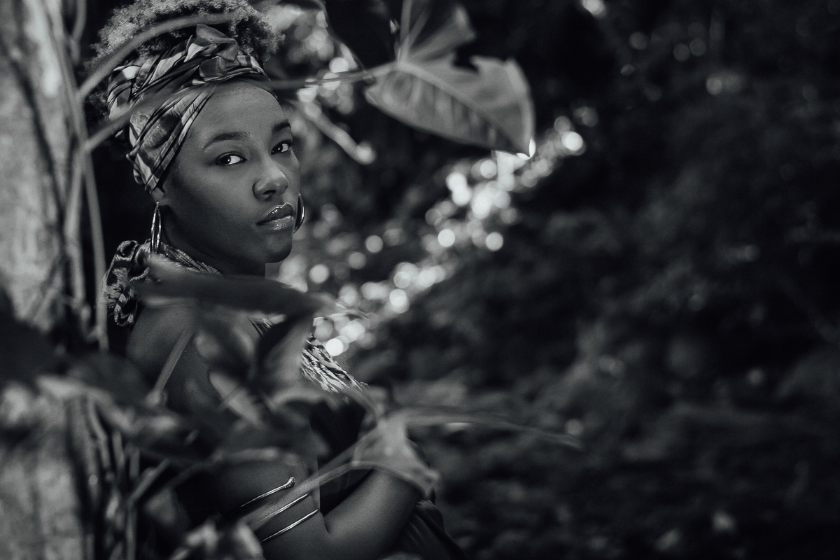 Gestante negra com vestido de estampa africana entre as folhas na mata