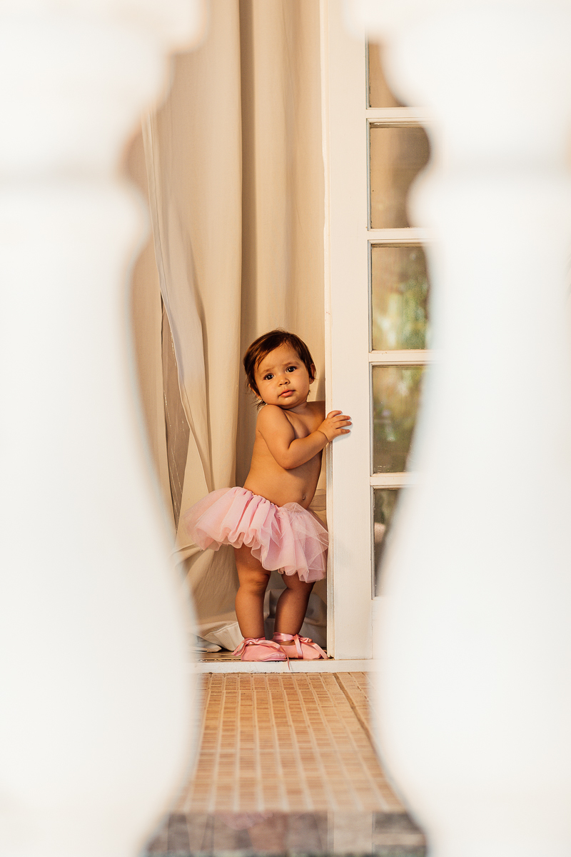 Bebê menina vestida de bailarina fazendo pose na porta 