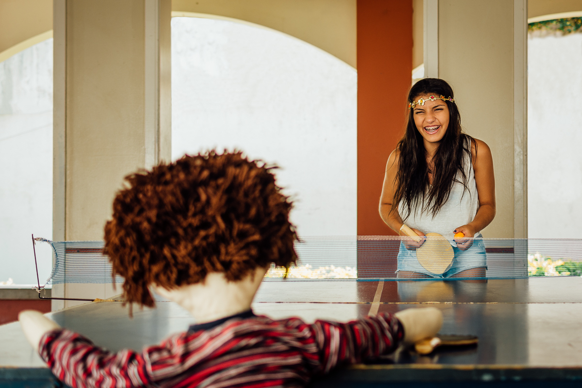 Menina jogando ping pong com o boneco de infância