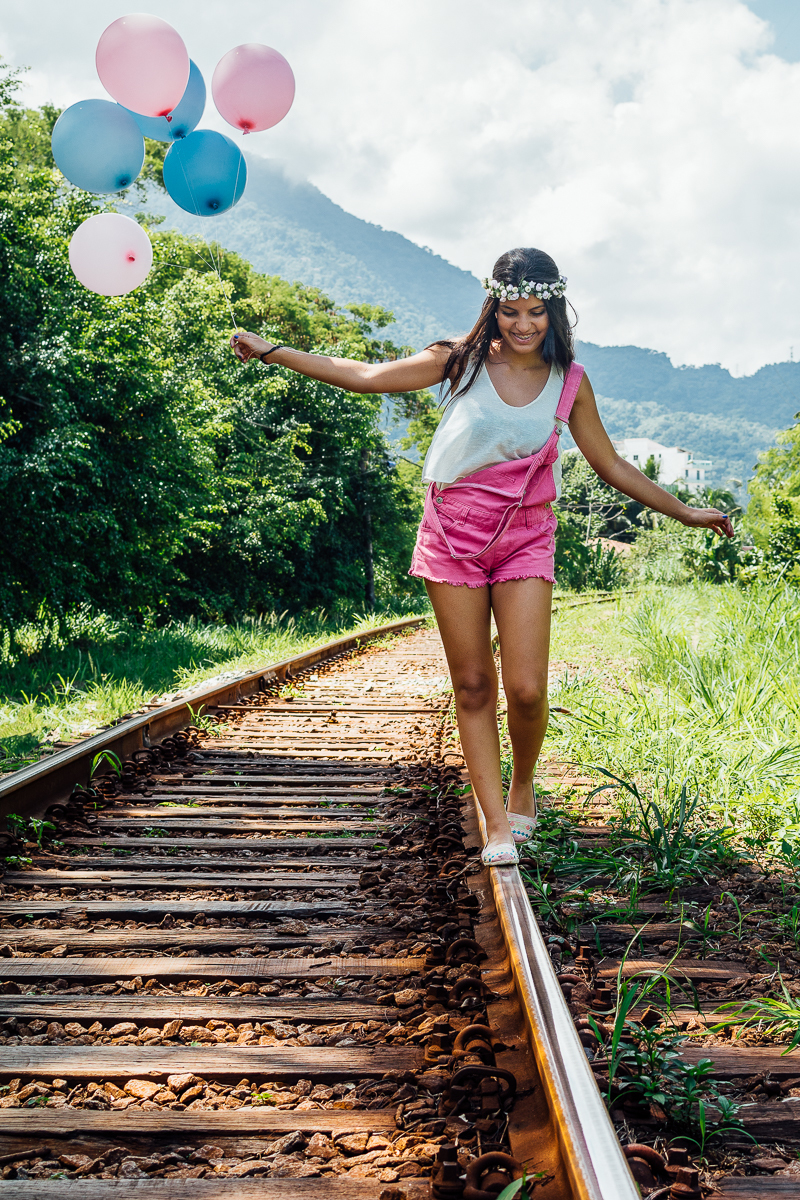 Menina andando na linha do trem de macacão rosa