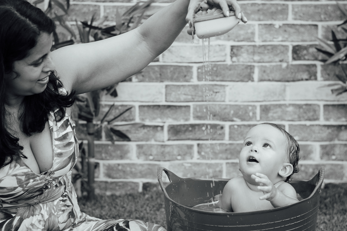 Mamãe brincando com o bebê no banho com o barquinho