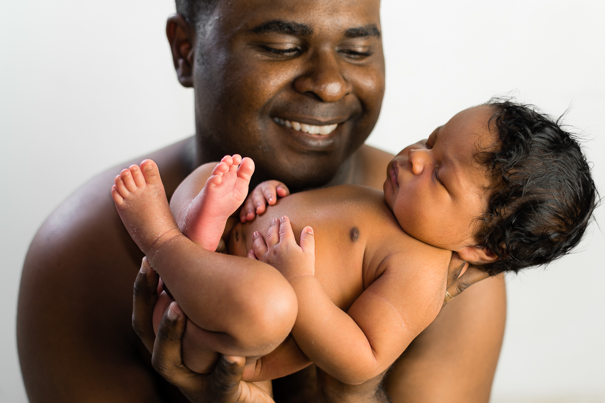 Pai sorrindo para o seu bebê e observado enquanto ele dorme, e pega o bebê em suas mãos