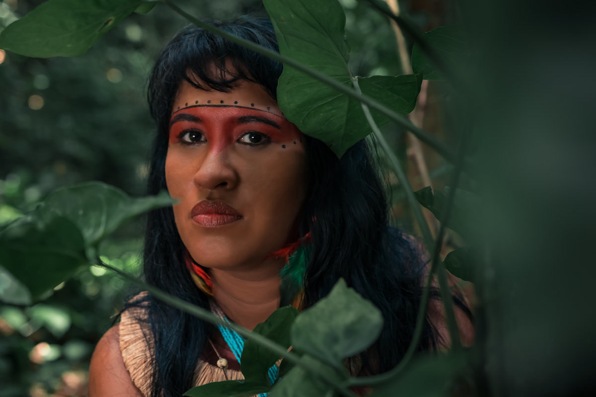 Índia escondida entre as folhas verdes atras de uma arvore, em uma cachoeira na. Fazenda Muriqui 