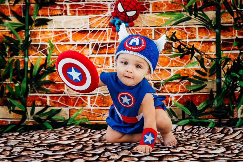 bebê fantasiado de capitão america segurando o escudo no ensaio cake smash com o tema vingadores bebê