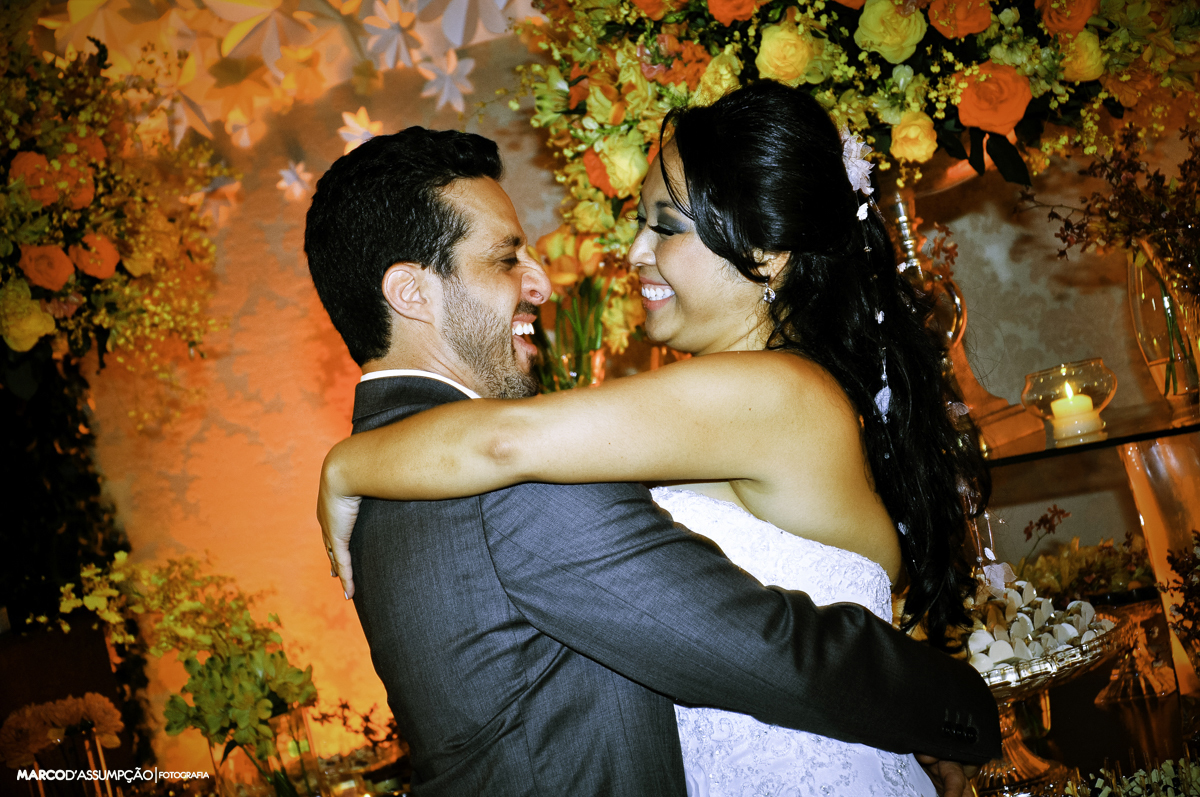 casal se olhando felizes em frente das flores