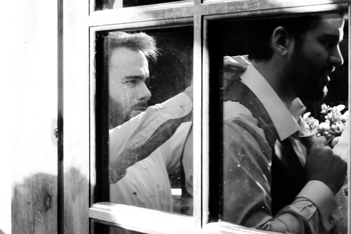 noivo se arrumando no reflexo de vidro