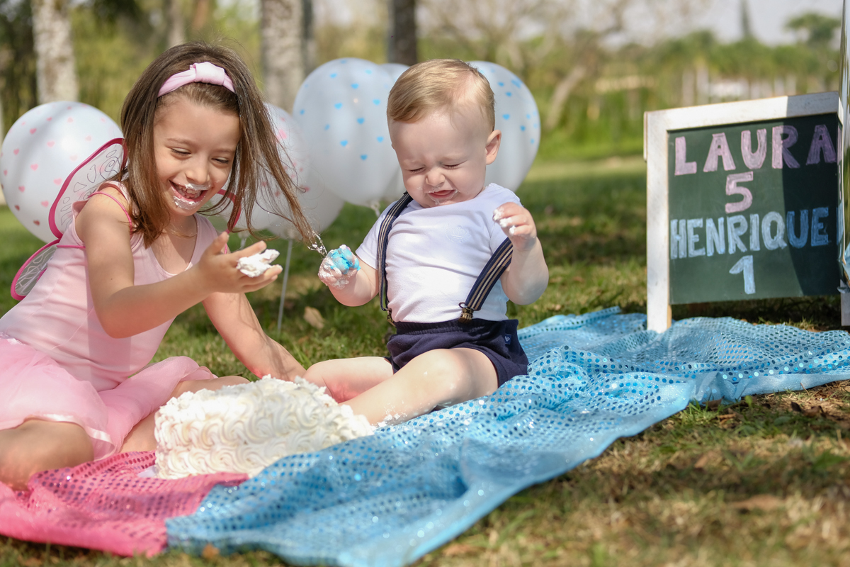 irmãos brincando com bolo em smash the cake