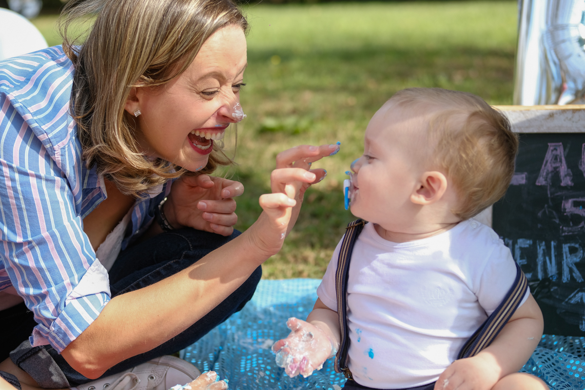 mamae passando recheio de bolo no nariz do filho