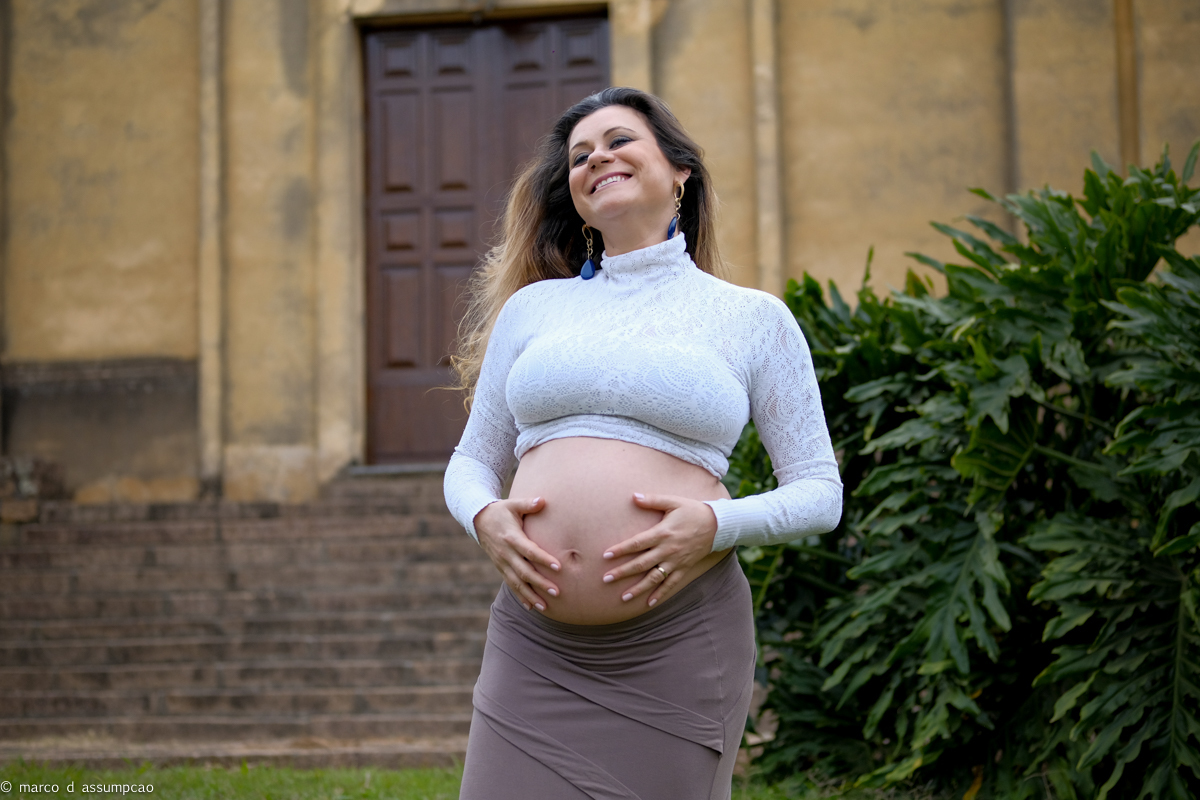 gestante sorrindo  em frente a igreja antiga