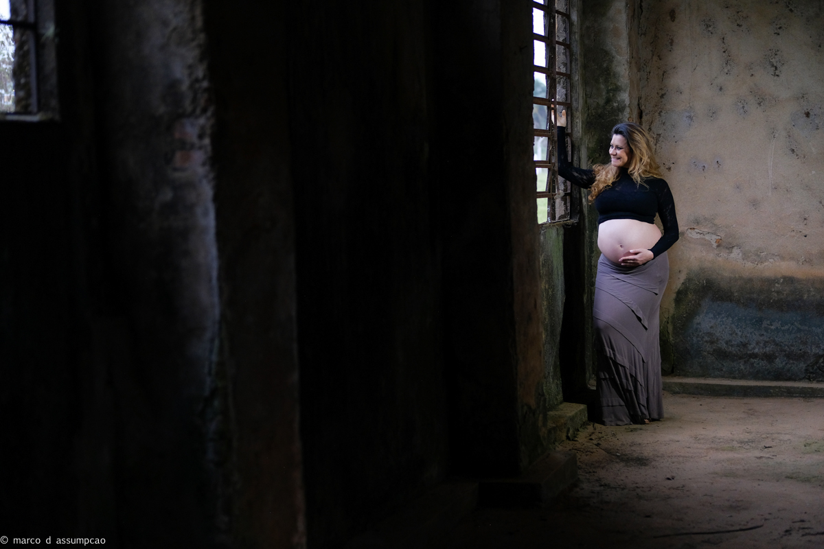 gestante ao lado de janela em construção antiga