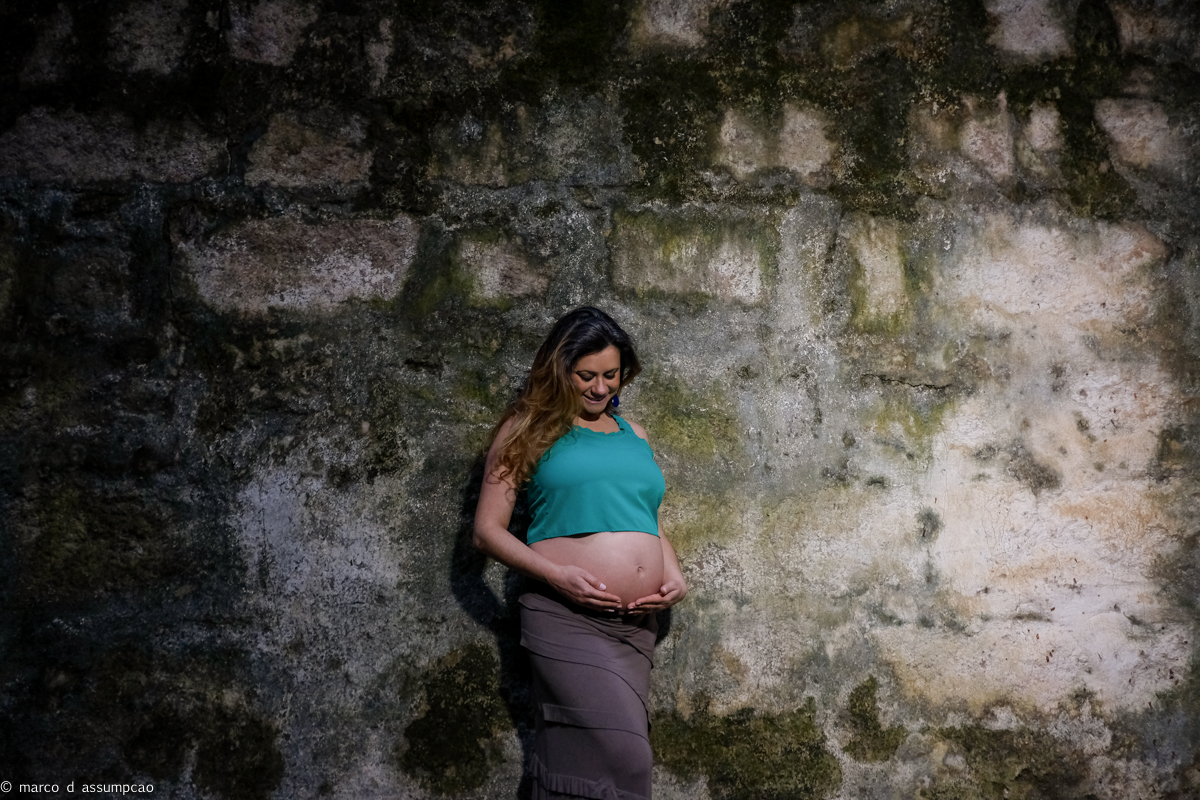 gestante encostada em parede rustica