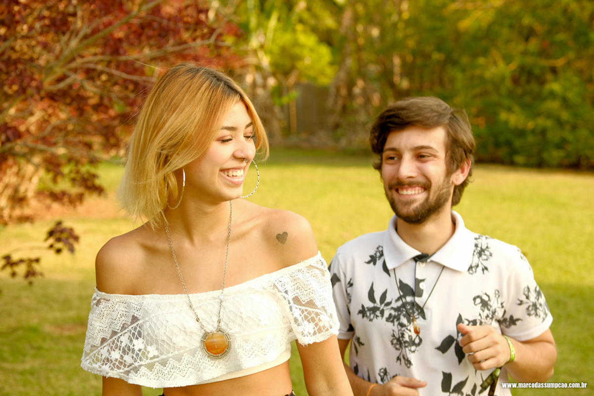 casal feliz e sorrindo entre as arvores