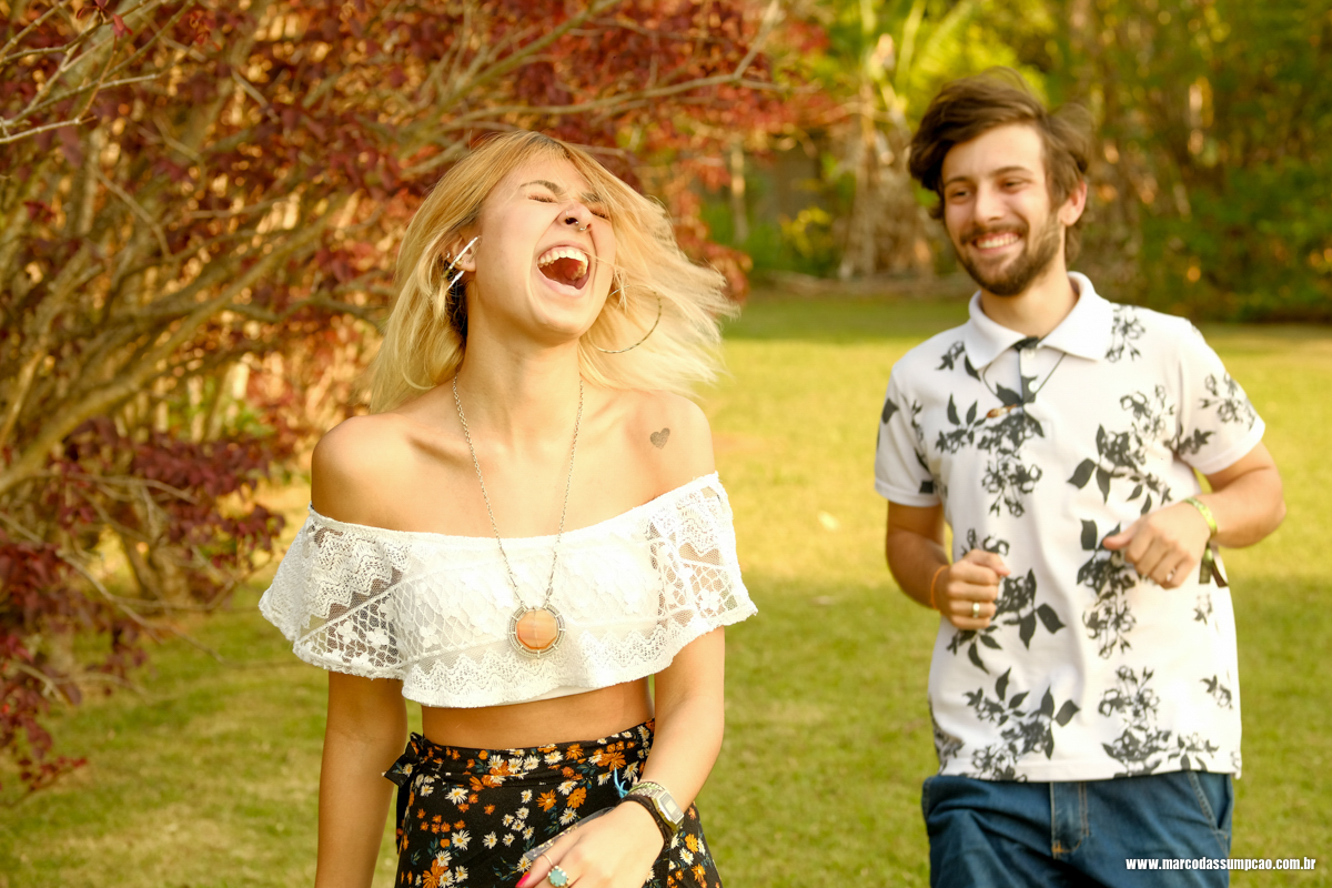 casal feliz e sorrindo entre as arvores