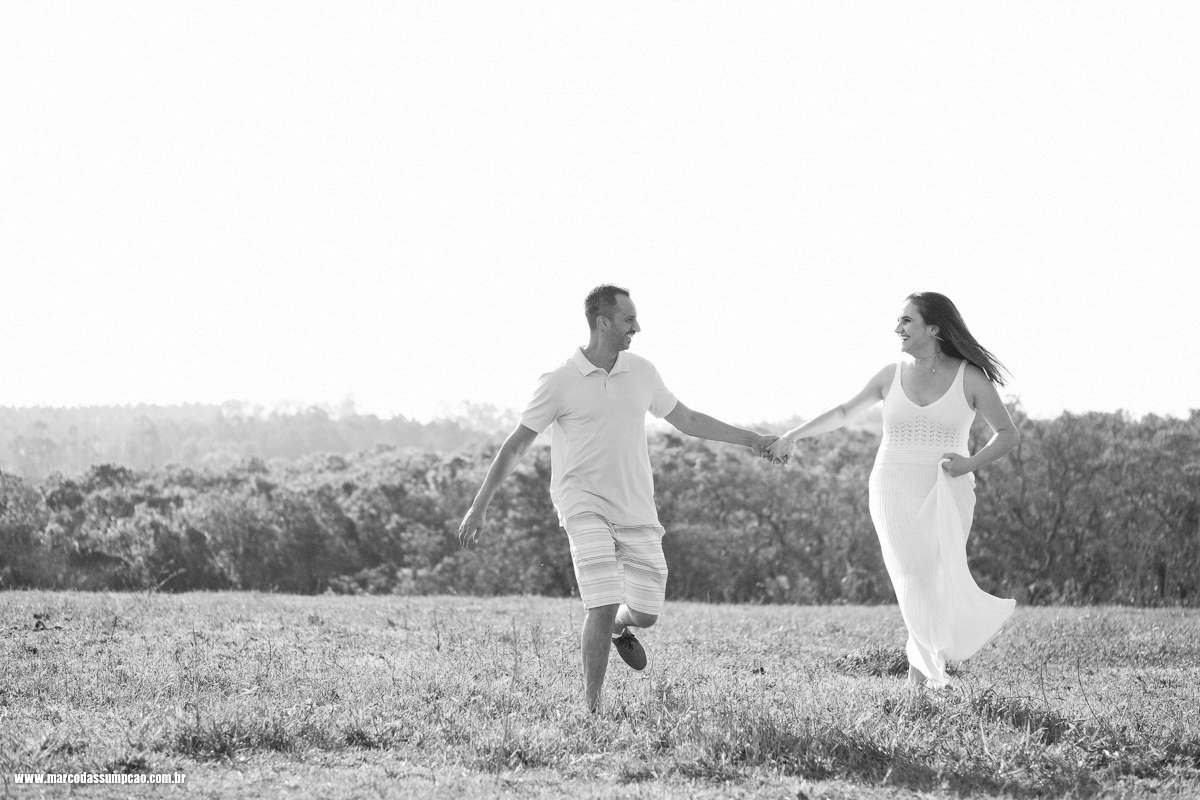 casal correndo em gramado de fazenda em foto preto e branco