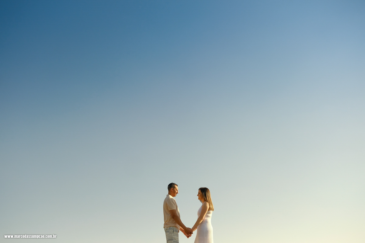 casal de maos dadas com o ceu azul