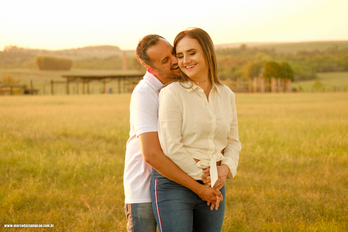 noivo abraçando a noiva por tras e beijando seu pescoço