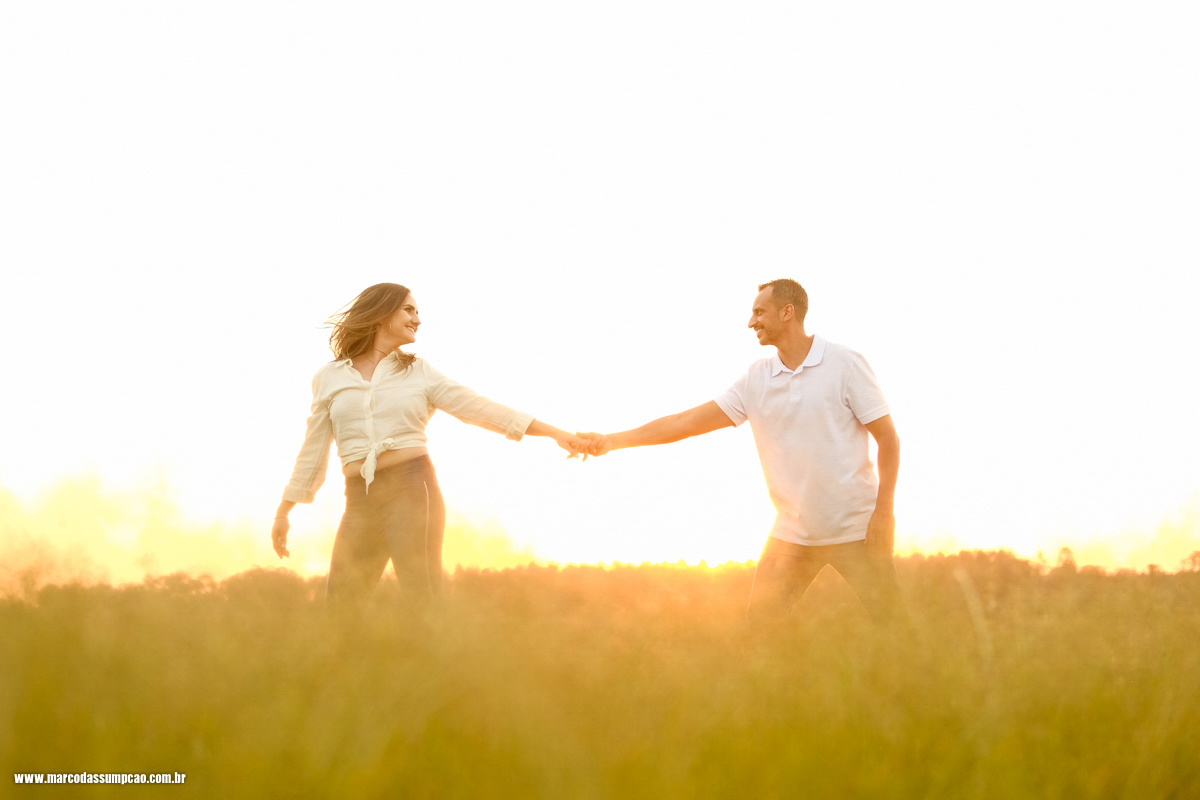 casal dancando no meio do feno em fazenda com por do sol ao fundo