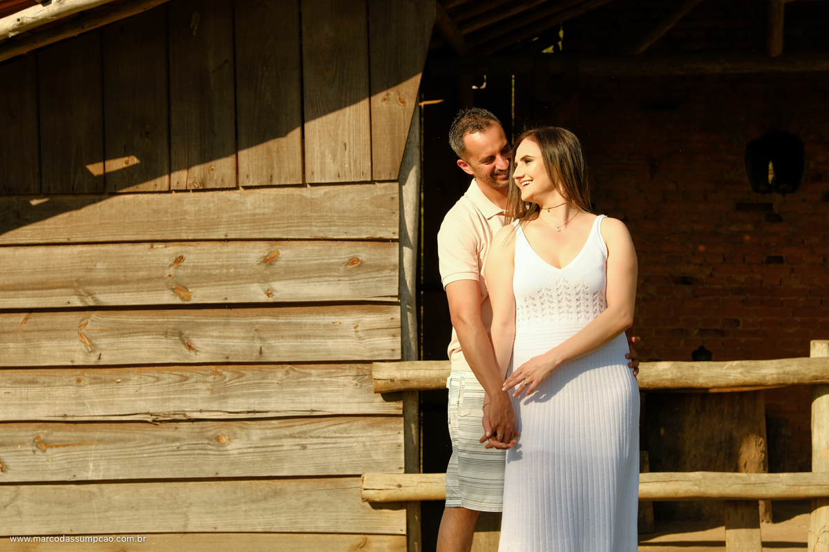 casal de maos dadas sorrindo em frente a rancho de fazenda