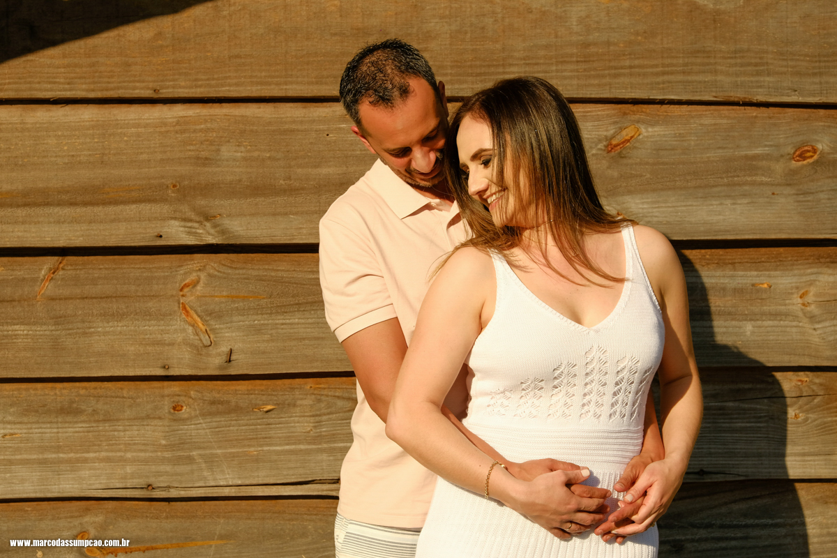 casal abracados  com a mao na cintura encostados em parede de madeira