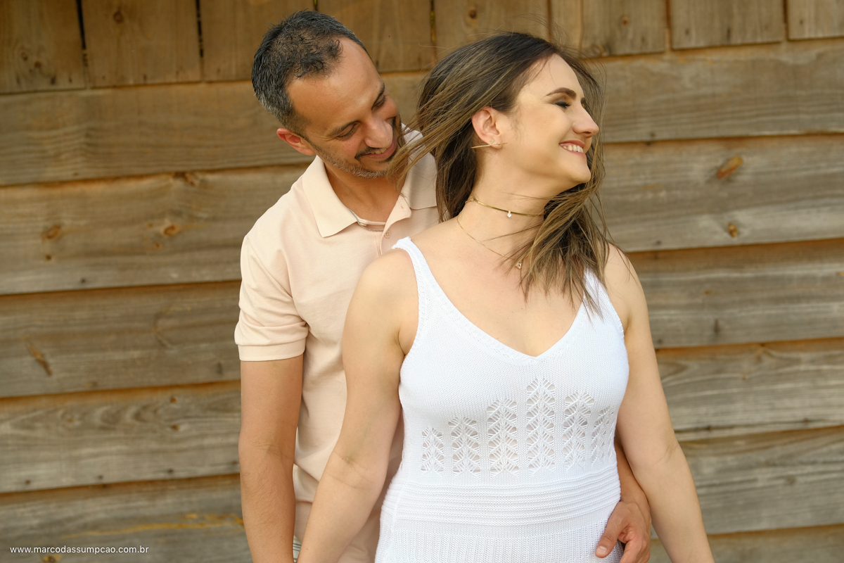 noiva sorrindo olhando ao lado enquanto noivo lha seu cabelo.