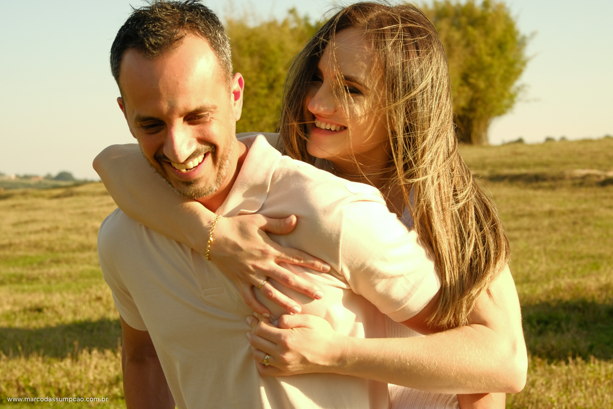 noiva apoiada nas costas do seu noivo sorrindo