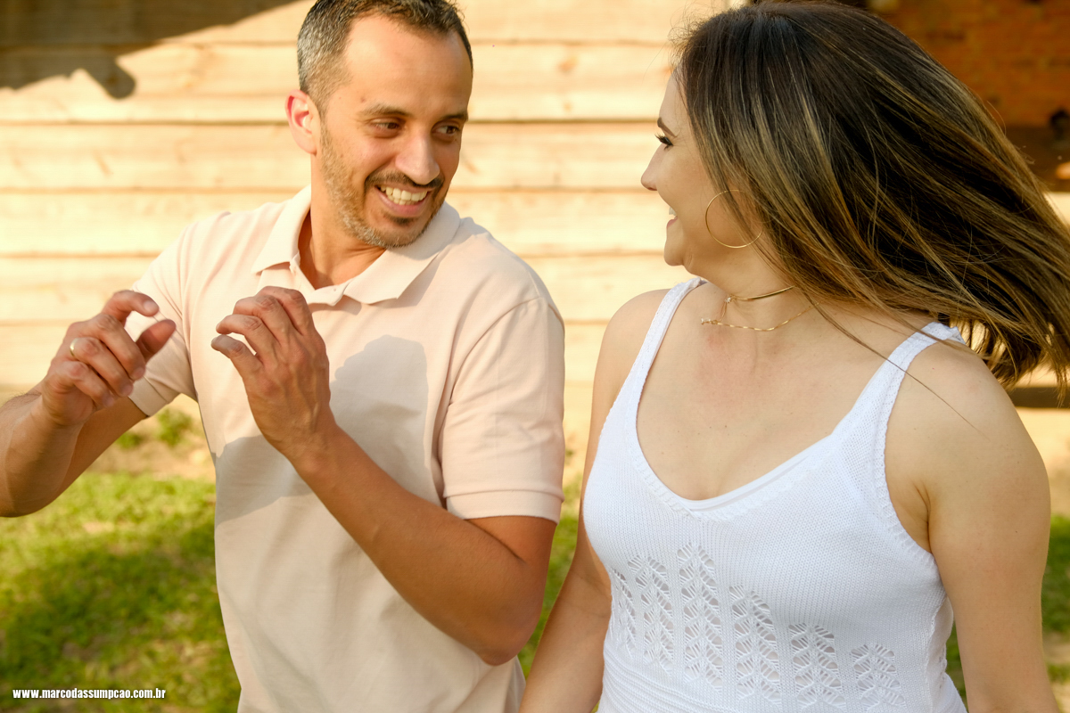 casal pulando e brincando em frente a rancho de fazenda