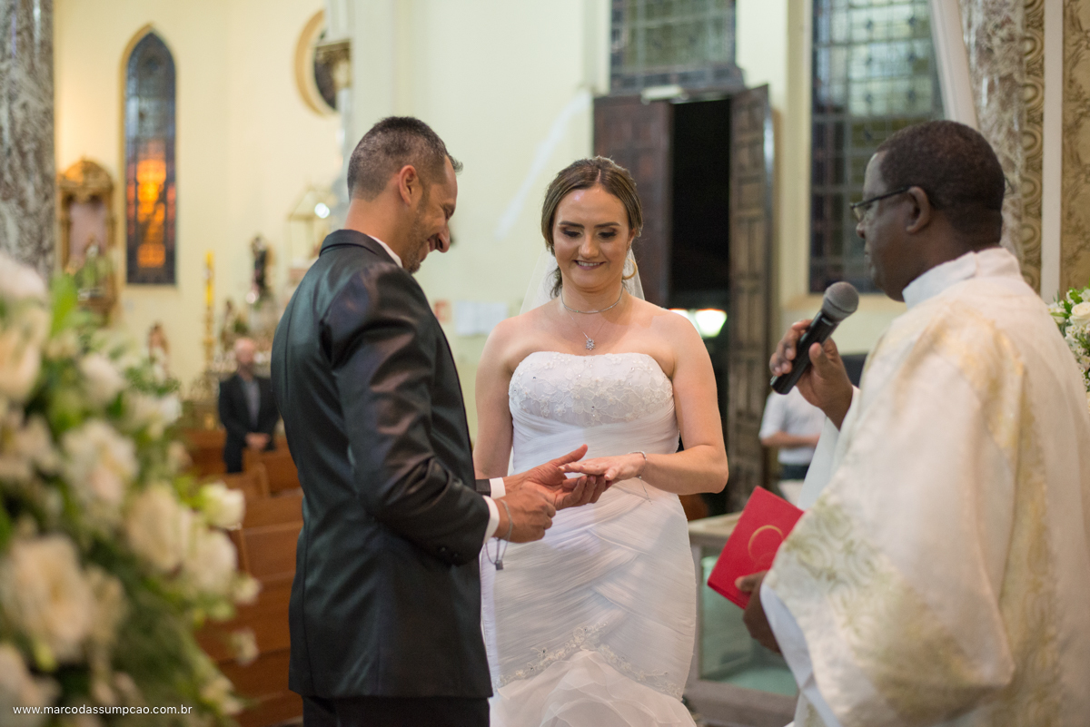 noivo colocando alianca de casamento na mao da noiva