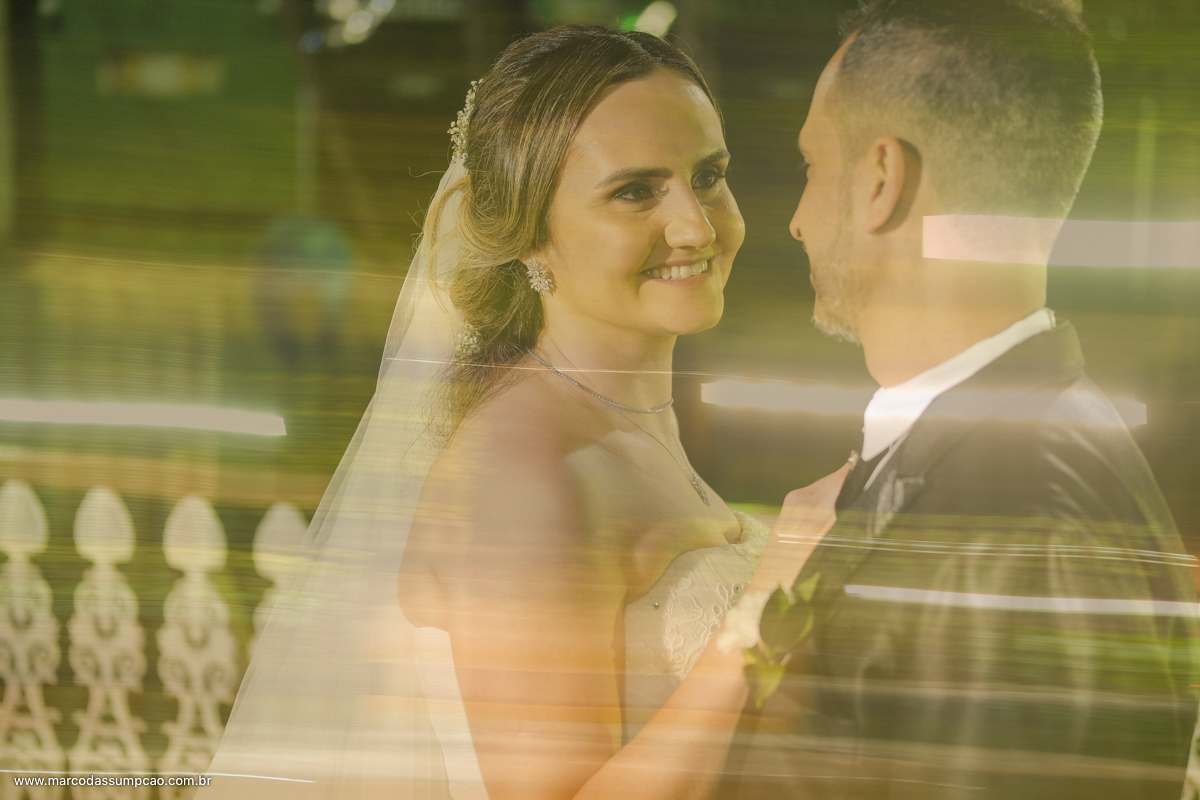 noivos sorrindo em frente a igreja com luzes