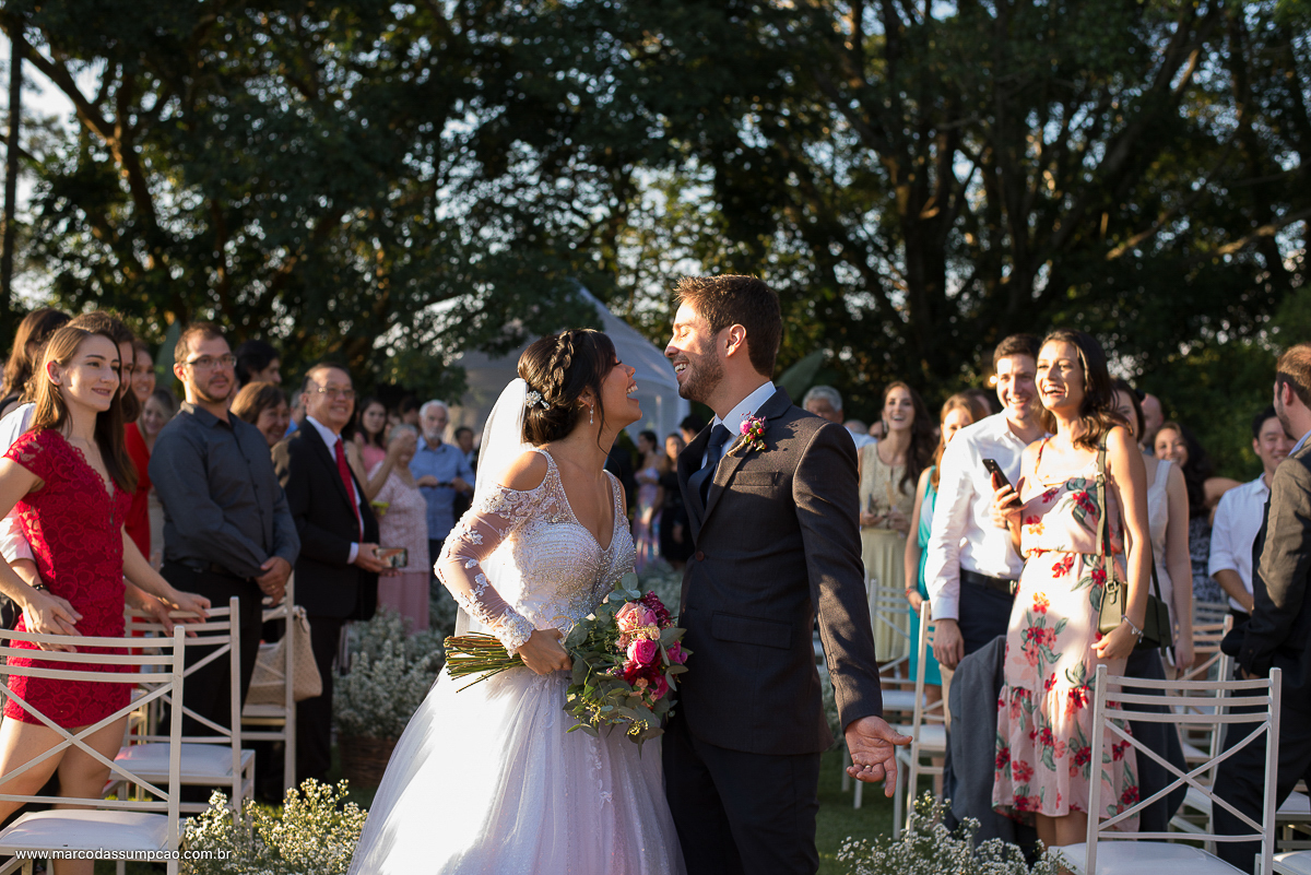 enfim casados noivos sorrindo no final do corredor na saida da cerimonia