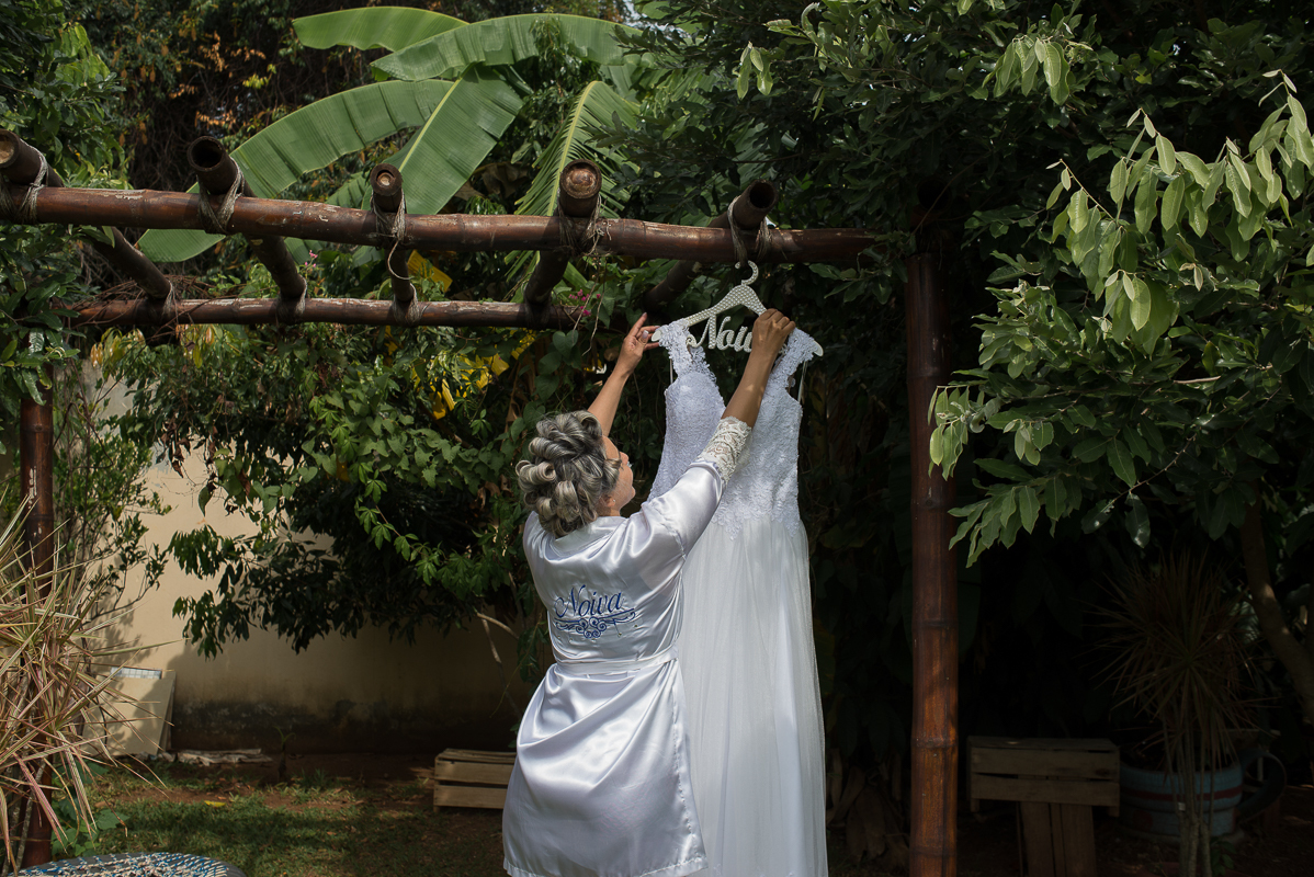 noiva pegando seu vestido pendurado no pergolado