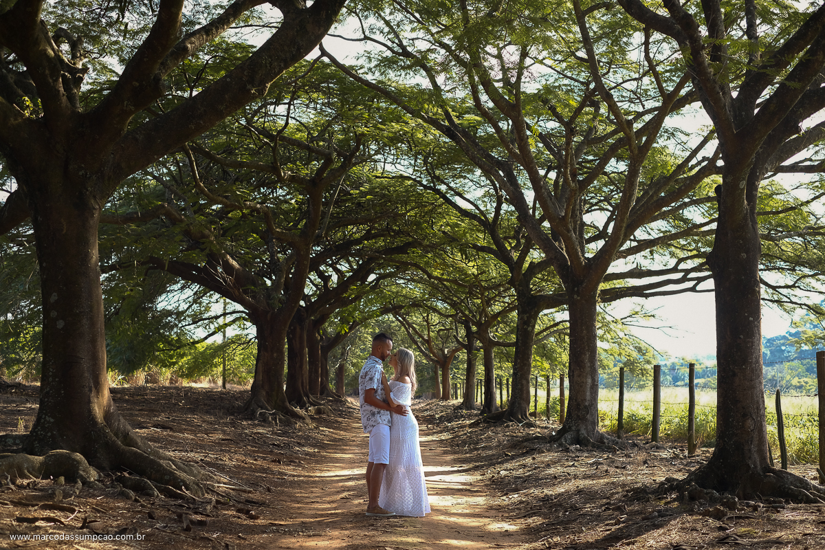casal se abracando na rua de terra entre as arvores