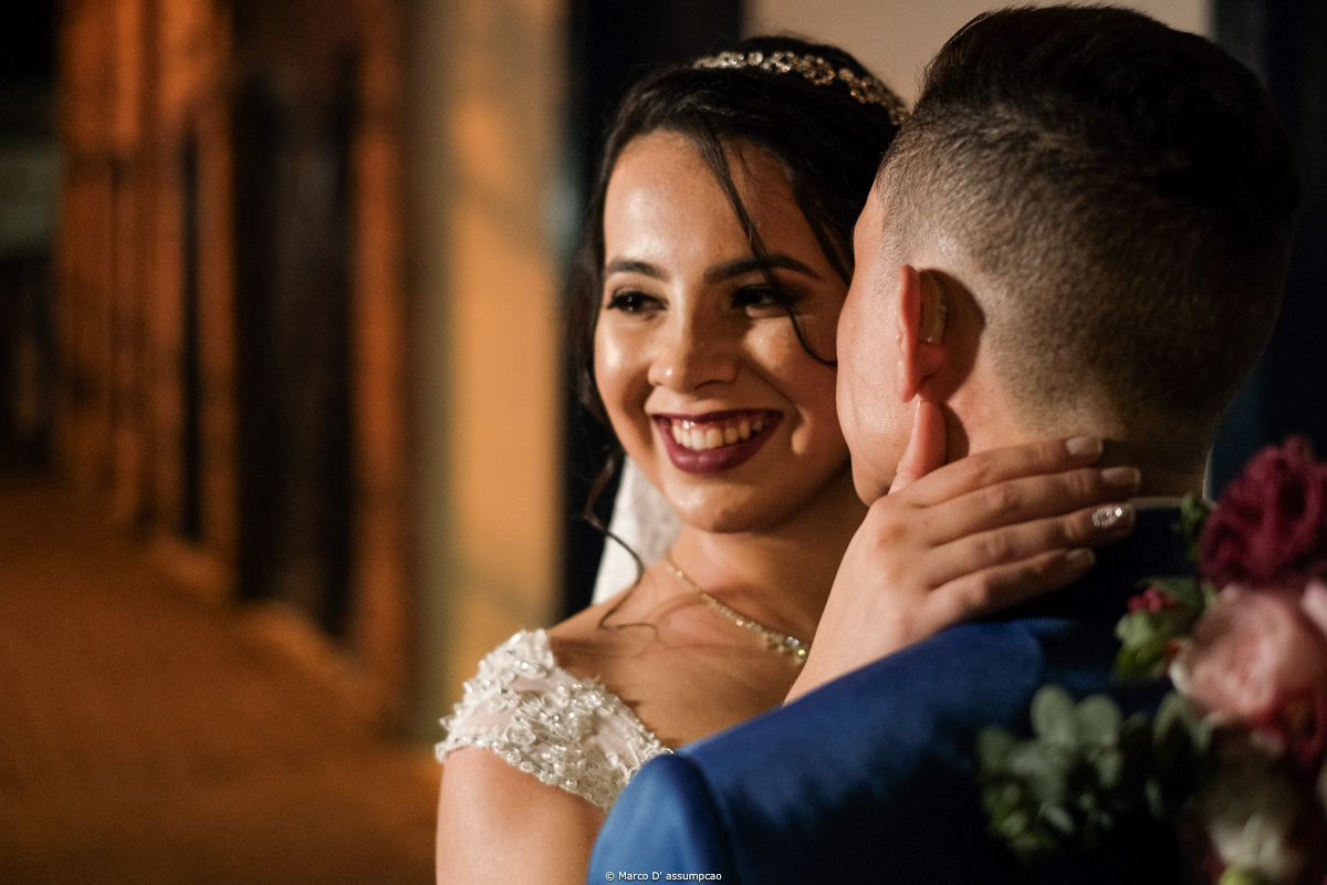 noiva sorrindo com noivo beijando seu pescoco