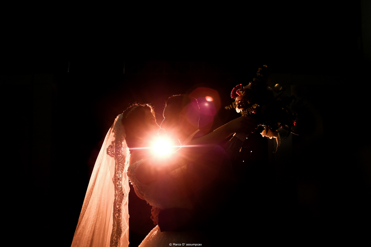 noivos se beijando com luzes de flash por tras