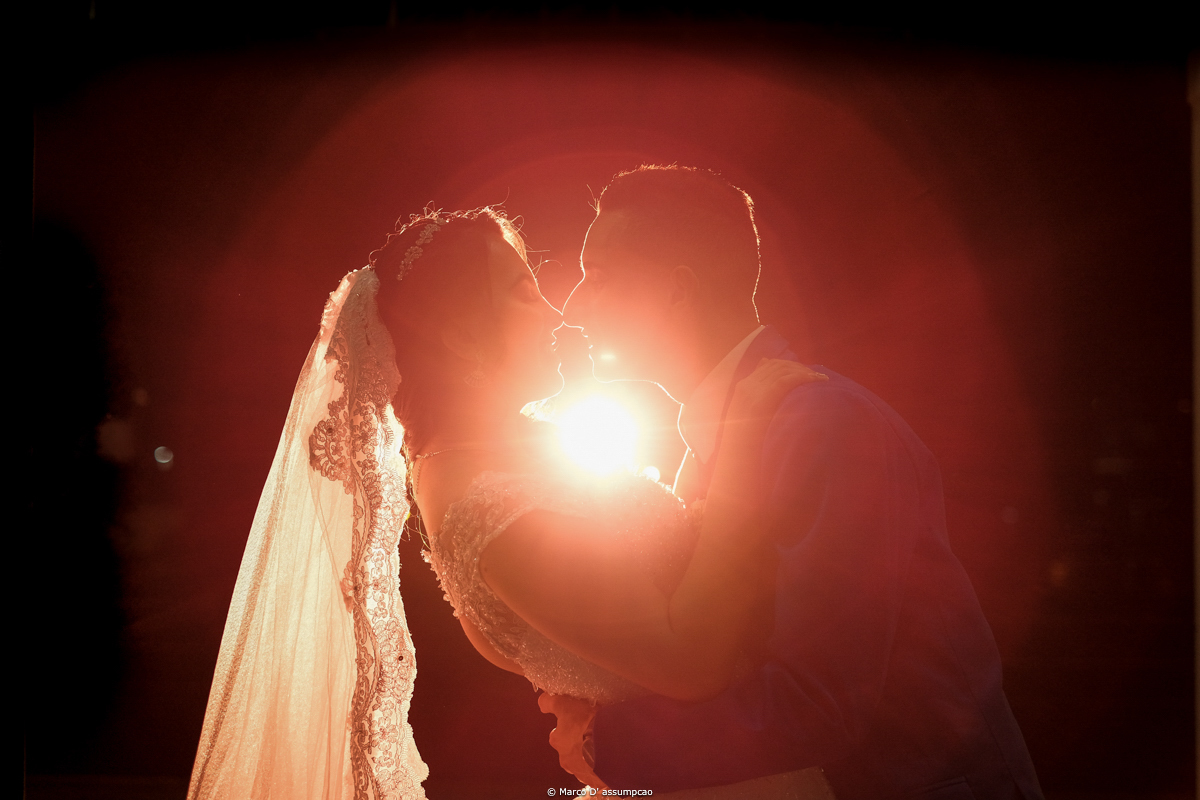noivos se beijando com luzes de flash por tras