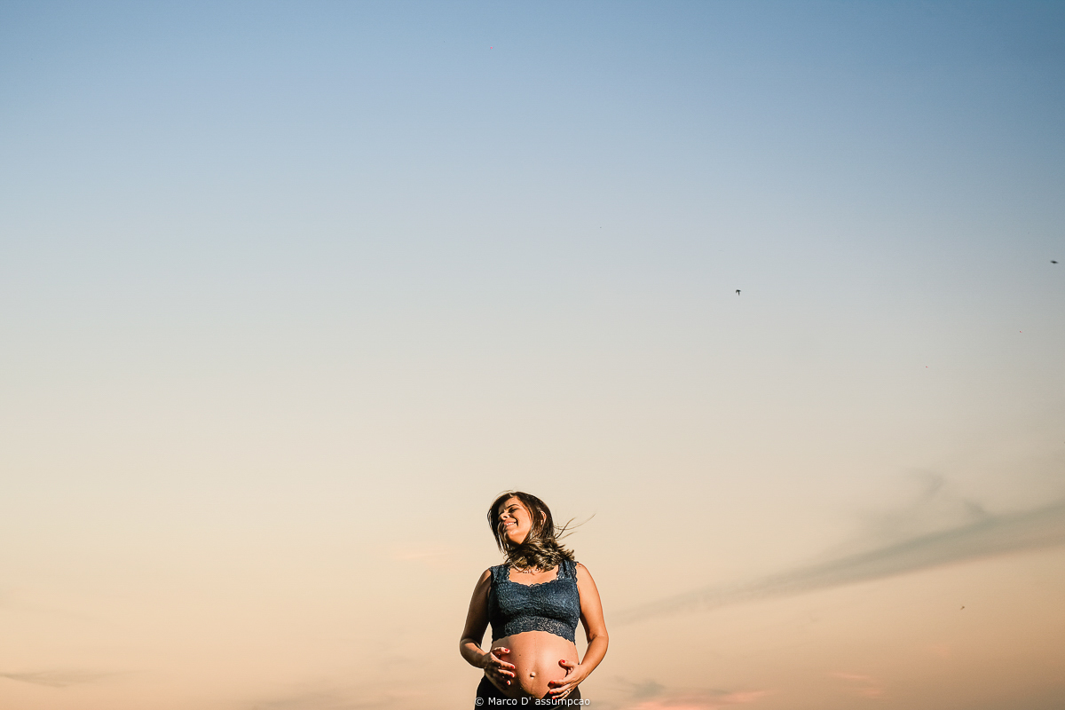 gestante com as maos na barriga com o ceu ao fundo